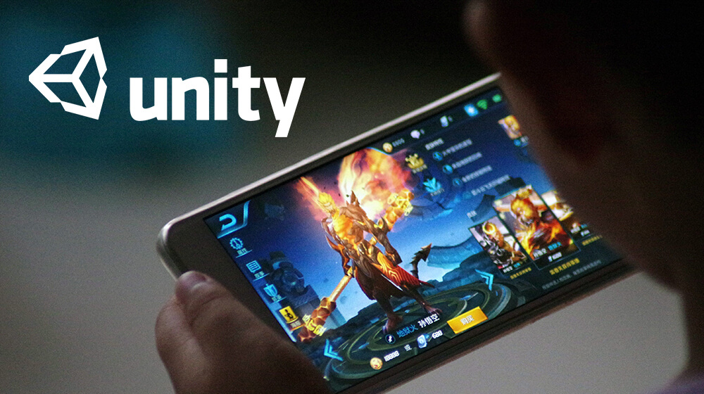 A person holding a smartphone playing a mobile game with the Unity logo displayed.